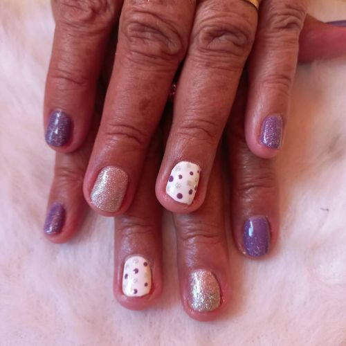 Uñas moradas junto a doradas y lunares